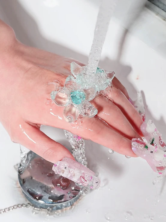 Supplied photograph of a translucent flower accessory on a hand under running water