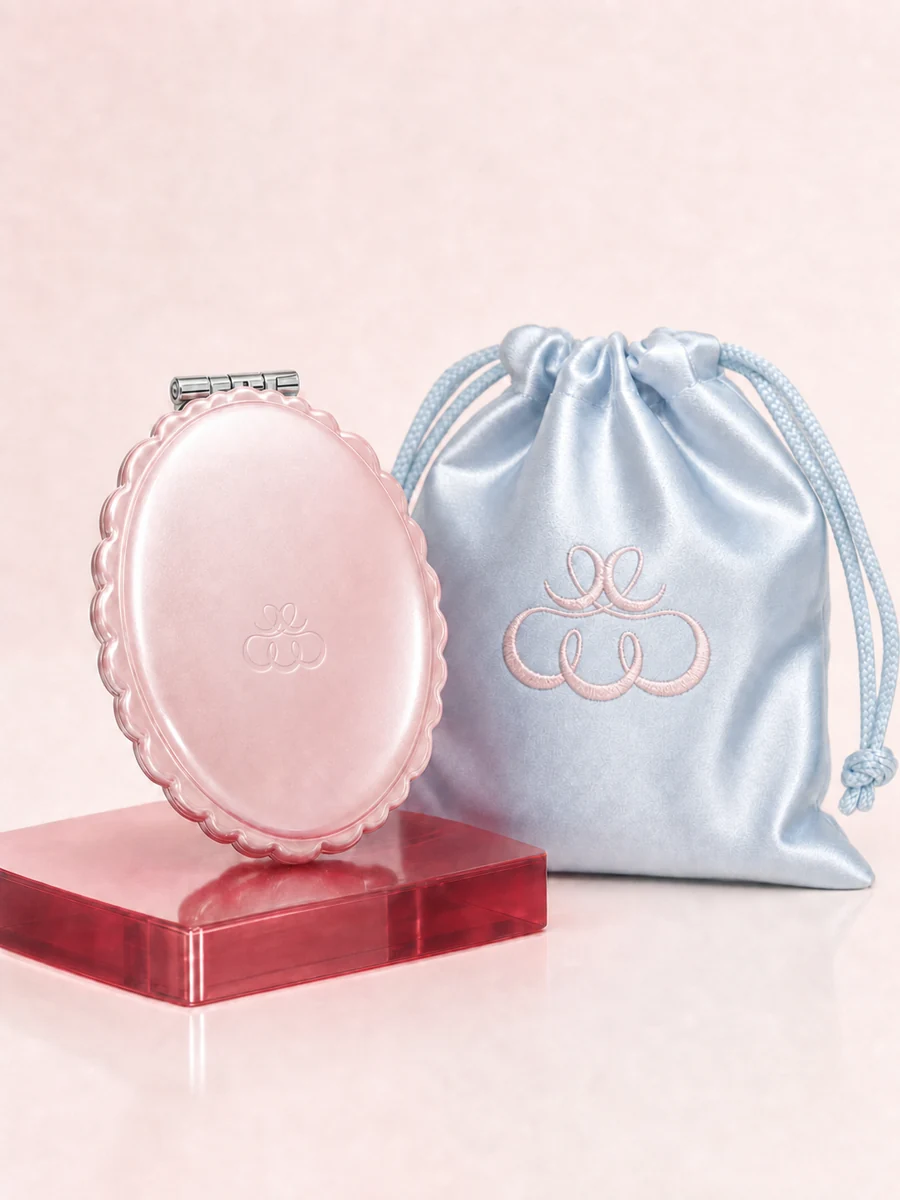 Pink oval compact with a blue satin drawstring pouch