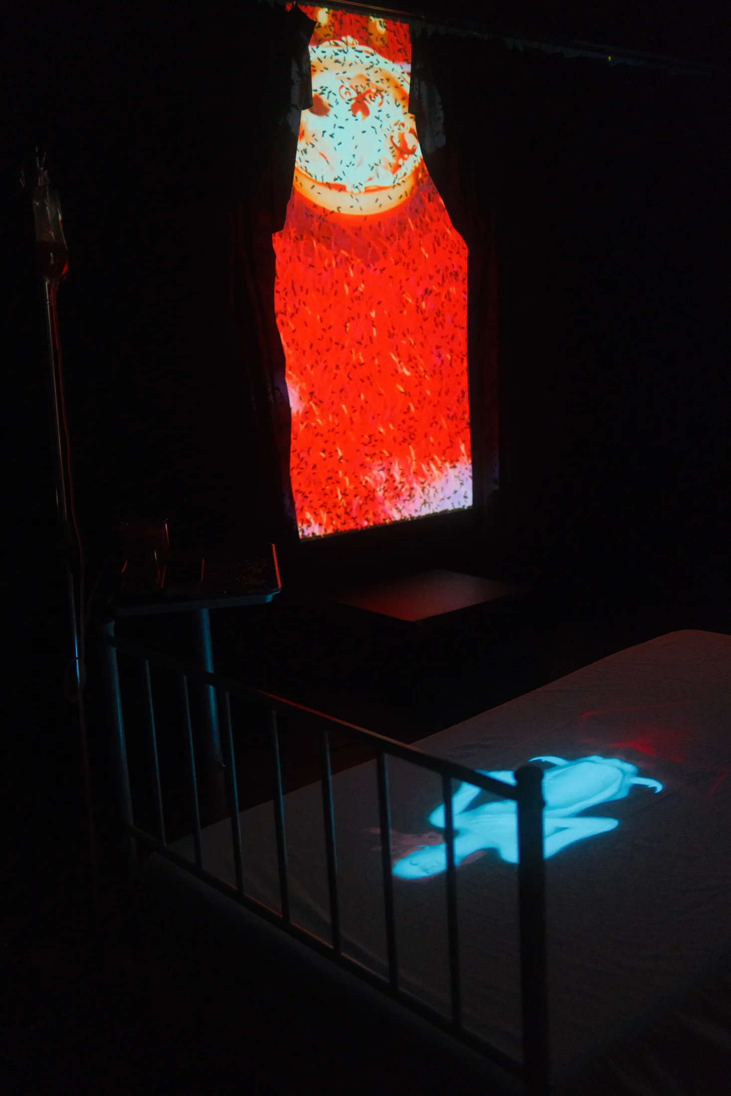 A red and white figure projected vertically above a glowing bed