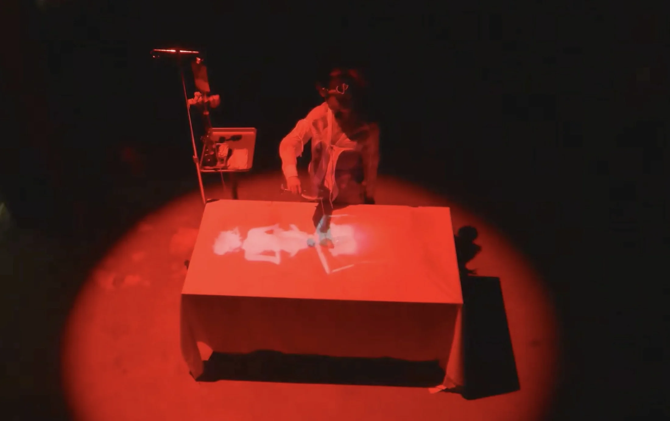A performer standing behind a red-lit table