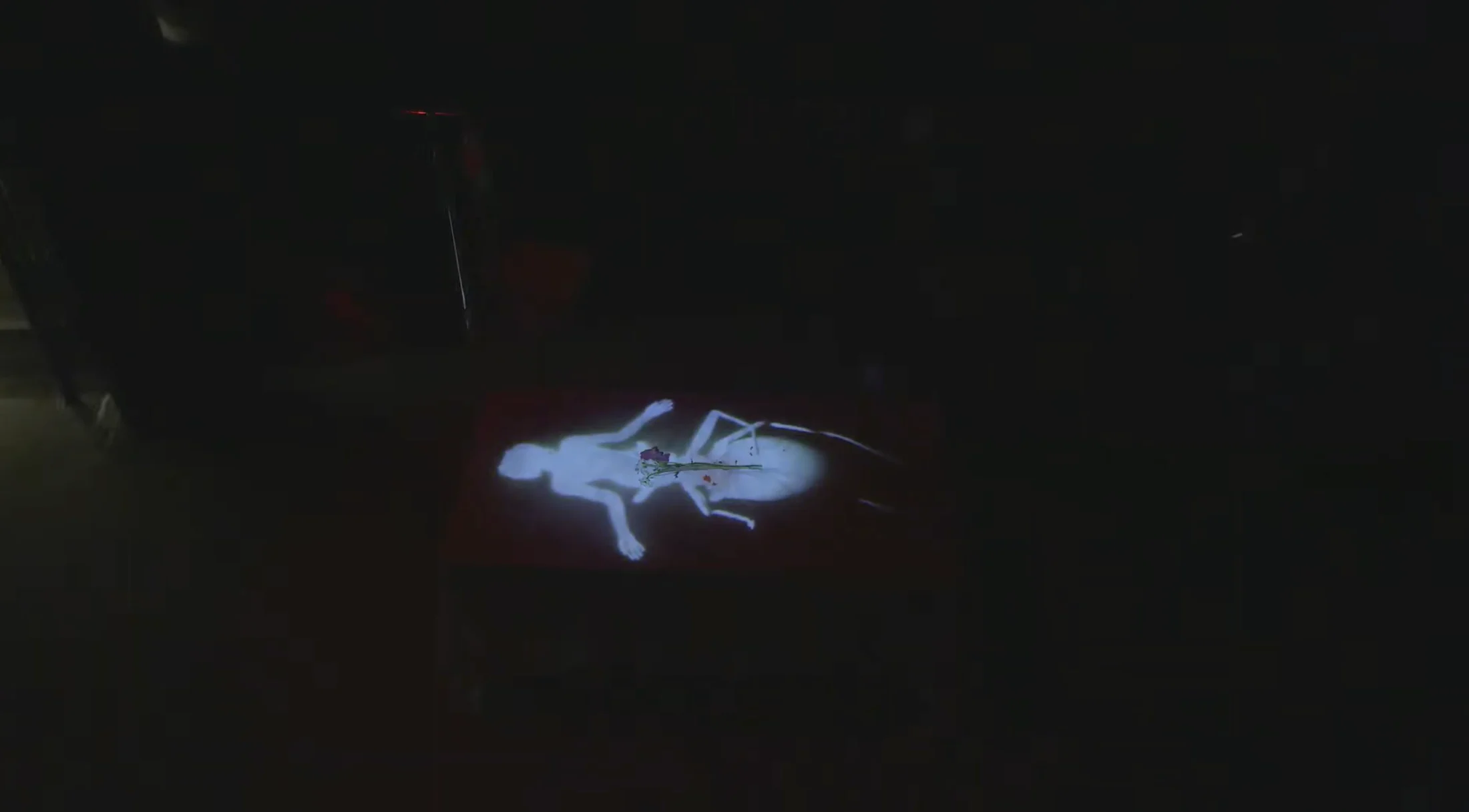 A pale projected body remains as the stage darkens